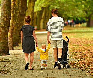 fotografía de una familia: madre, padre e hijo pequeño paseando por un parque