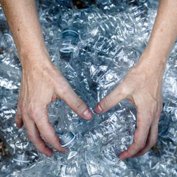 manos de mujer cogiendo envases de botellas de plástico