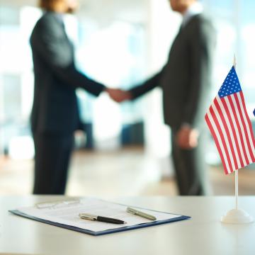 imagen de dos hombres dandose la mano junto a las banderas de Estados Unidos y la Unión Europea