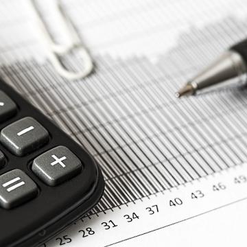 imagen de calculadora sobre un papel con datos económicos y un bolígrafo