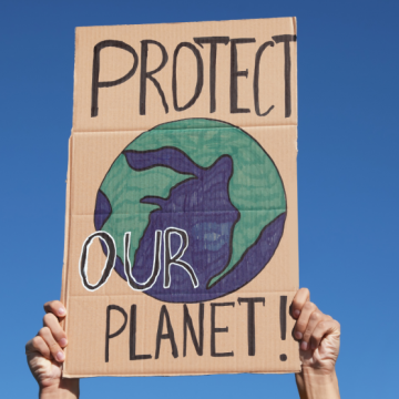 Manos sosteniendo letrero con un dibujo del globo terráqueo y el lema 'Protect our planet'