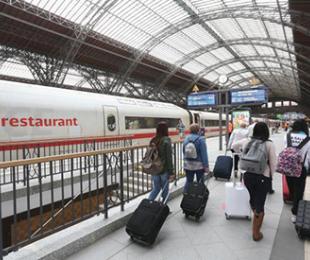 fotografía de una estación de tren con varias pasajeras en el andén llevando maletas