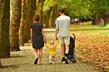 fotografía de una familia: madre, padre e hijo pequeño paseando por un parque