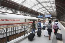 fotografía de una estación de tren con varias pasajeras en el andén llevando maletas