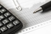 imagen de calculadora sobre un papel con datos económicos y un bolígrafo
