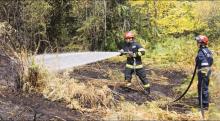 fotografía de dos bomberos forestales apagando un fuego en zona boscosa